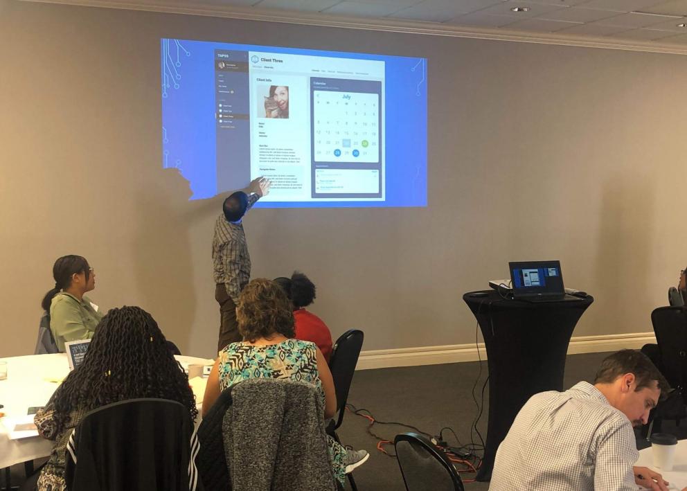 Graphic Designer Sean Blake presenting application designs for a client management and communication tool at a DCF workshop in 2019. 